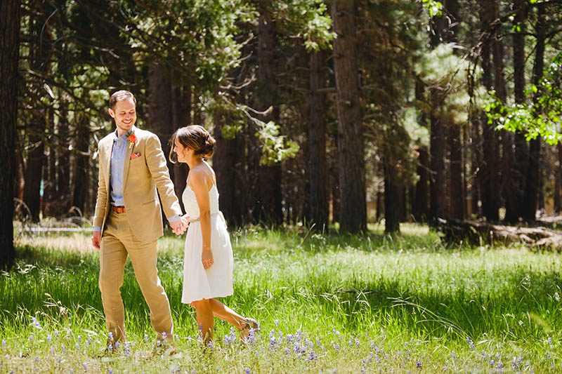 Bride and groom walking through an open meadow