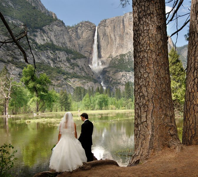 Wedding couple by the Merced River with Yosemite Falls